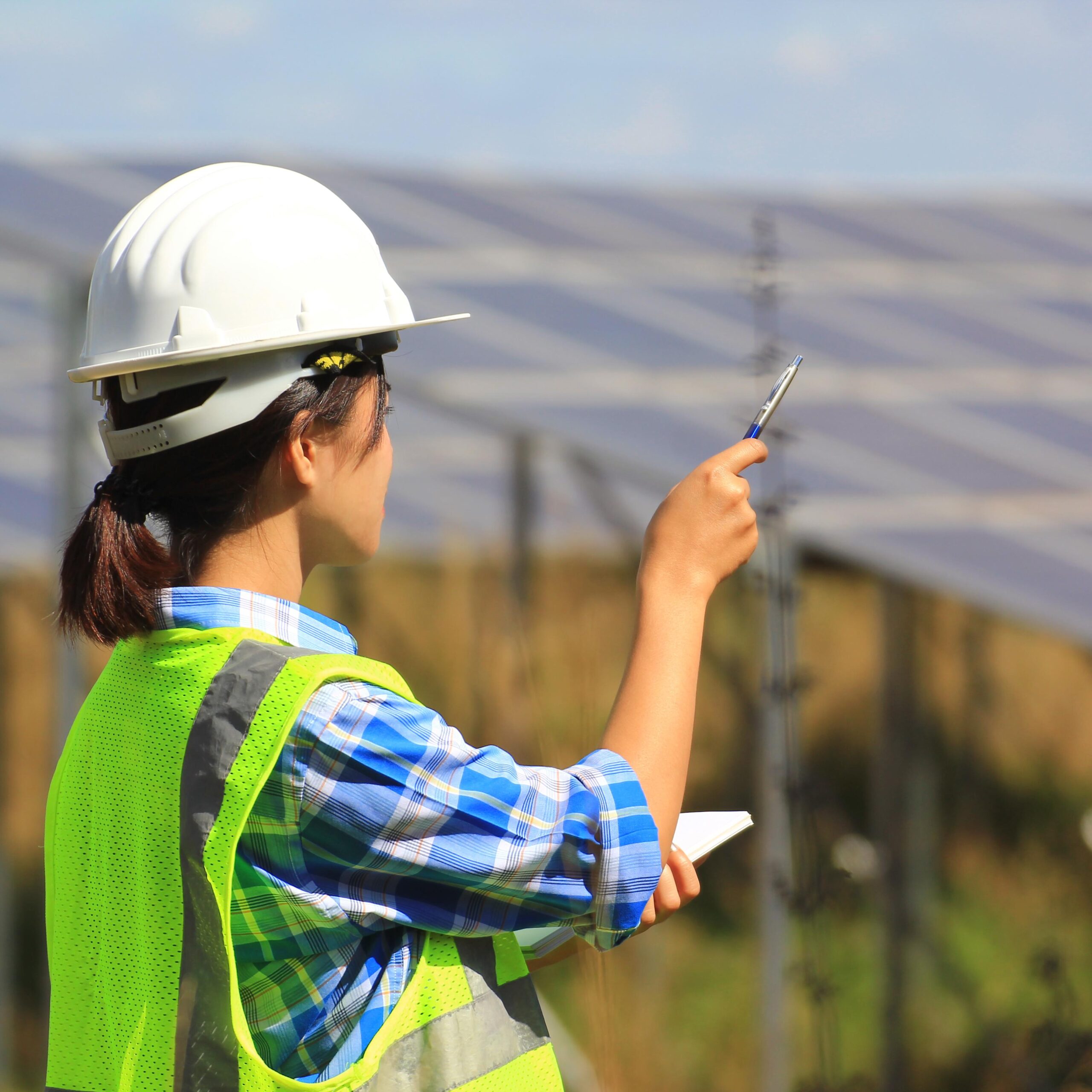 young woman engineer checking solar panel at solar power plant